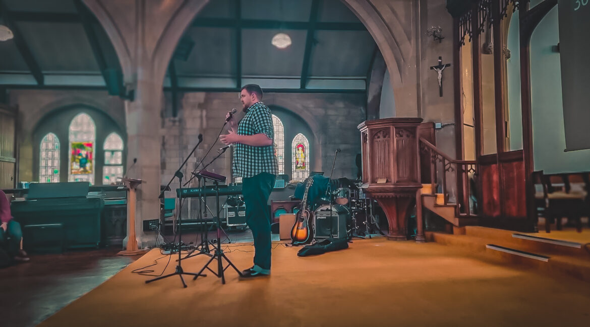 Curate Ben Notley stood talking at a microphone to the congregation of Ascension church